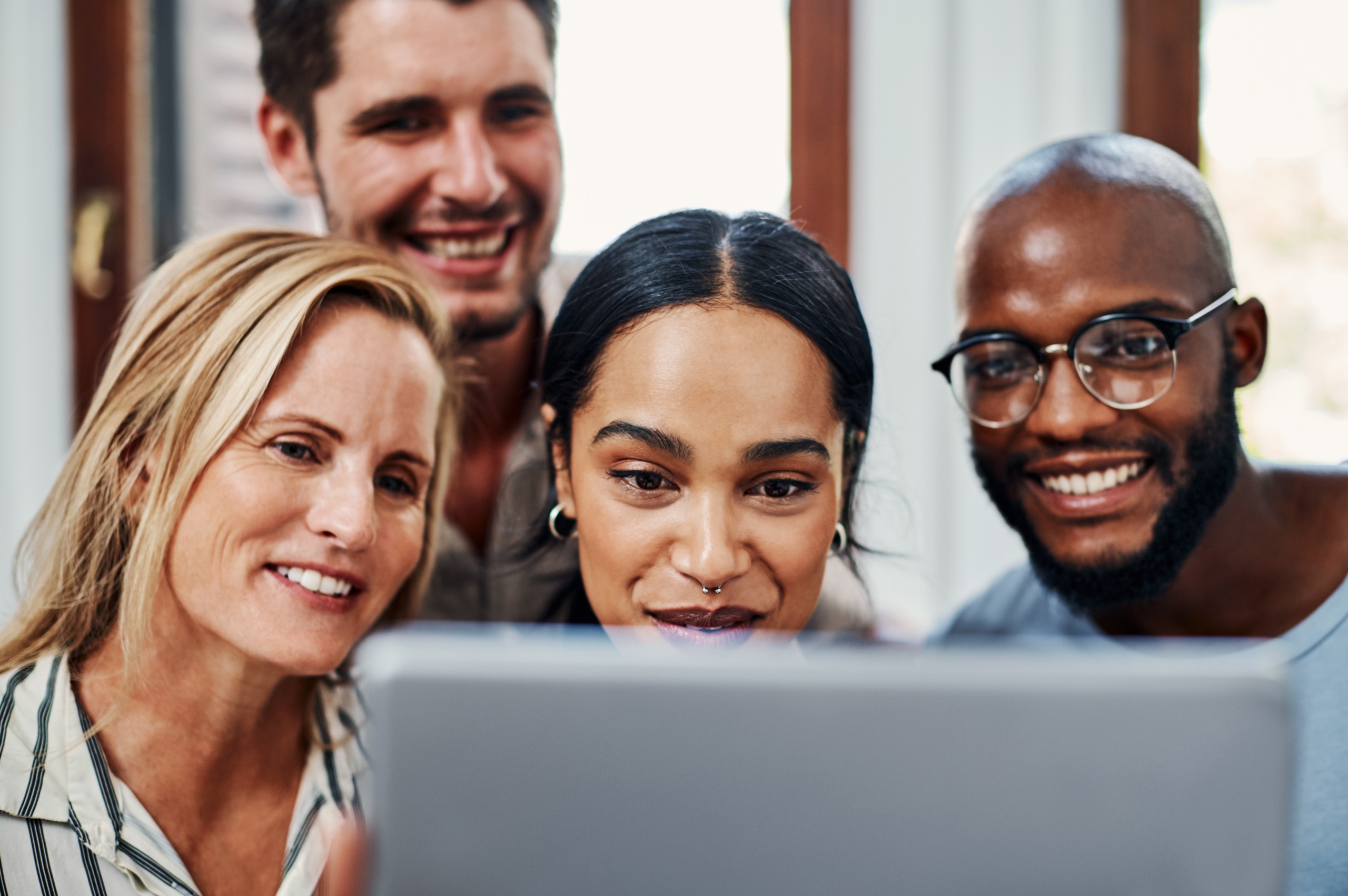 Groupe de personnes souriantes devant une tablette tactile.